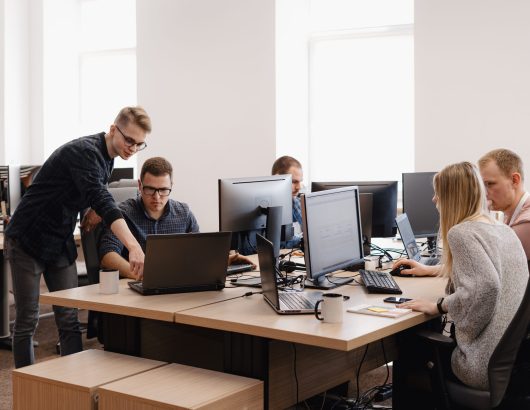 Full concentration at work. Group of young business people working and communicating while sitting at the office desk together with colleagues sitting in the background